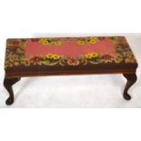 A reproduction long foot stool of rectangular form with needlework tapestry top on carved cabriole