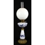 An Art Nouveau style oil lamp with clear glass bulbous shade and blue and white overlaid reservoir