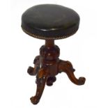 A Victorian carved walnut revolving piano stool with green leather top.