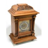 A German Art Nouveau carved walnut cased mantel clock, the brass face set with silvered chapter ring