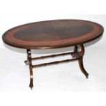 A reproduction mahogany veneered low coffee table of oval form, with leather inset border on lyre