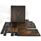 A collection of fourteen vintage stained wood letter press letters, the largest is an M, 59 x