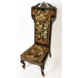 A Victorian carved walnut framed prayer chair upholstered in a floral tapestry material.Condition