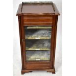 An Edwardian mahogany music cabinet with glazed doors, labelled shelves and brass three-quartered