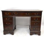 A reproduction mahogany knee-hole desk with brown leather inset top above an arrangement nine