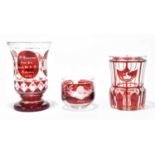 Three pieces of cranberry overlaid Bohemian glass to include a tumbler and two vases, height of