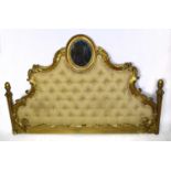 A reproduction gilt French headboard, the oval mirror with scrolling arms above the button backed