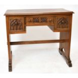 PRIORY; an oak writing table, with three drawers and linen fold carved detailing, on standard end