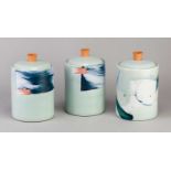 † ADAM FREW (born 1981); a trio of cylindrical porcelain jars and covers, two covered in celadon