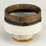 † ROBIN WELCH (1936-2019); a small stoneware pedestal bowl covered in bands of white and bronze