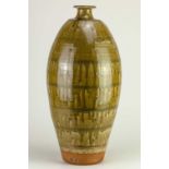 † PHIL ROGERS (1951-2020); a very tall stoneware bottle covered in green ash glaze with incised