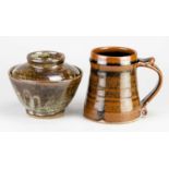 Leach Pottery; a stoneware mug covered in tenmoku breaking to kaki glaze, impressed pottery mark,
