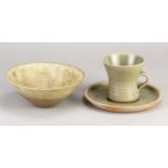 Leach Pottery; a stoneware cup and saucer covered in green glaze, impressed pottery marks, height