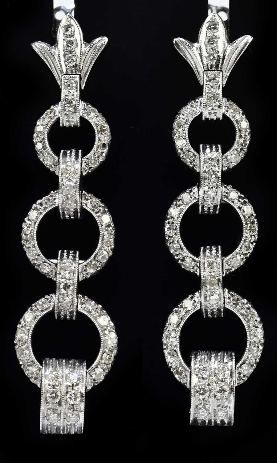 A pair of white metal and diamond Art Deco design drop earrings formed of three graduated hoops,