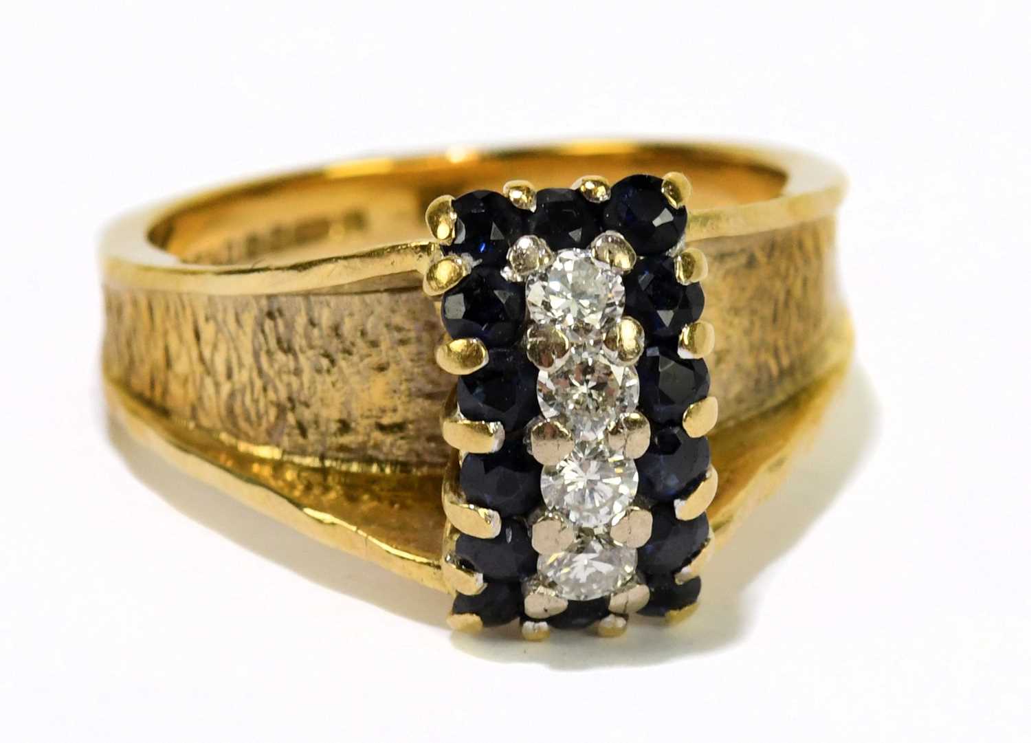 An 18ct yellow textured gold dress ring set with four brilliant cut diamonds flanked by sapphires,