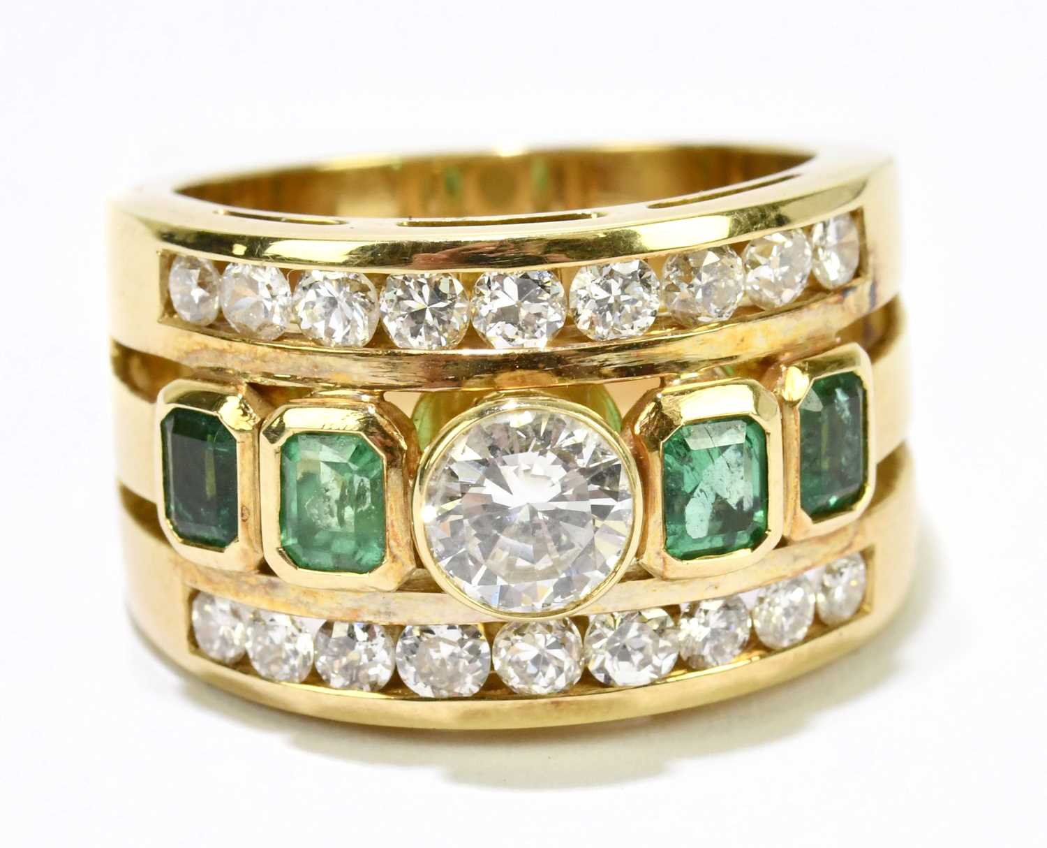 A yellow metal diamond and emerald three band ring, centred with a round brilliant cut collet set