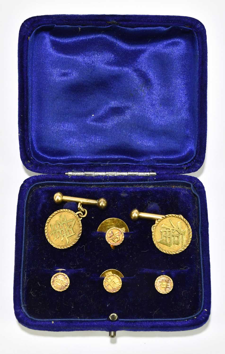 A pair of yellow metal cufflinks set with Chinese characters to the circular platforms and the