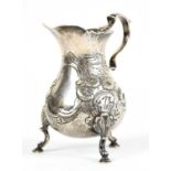 A George II hallmarked silver cream jug with later Victorian floral embossed decoration and