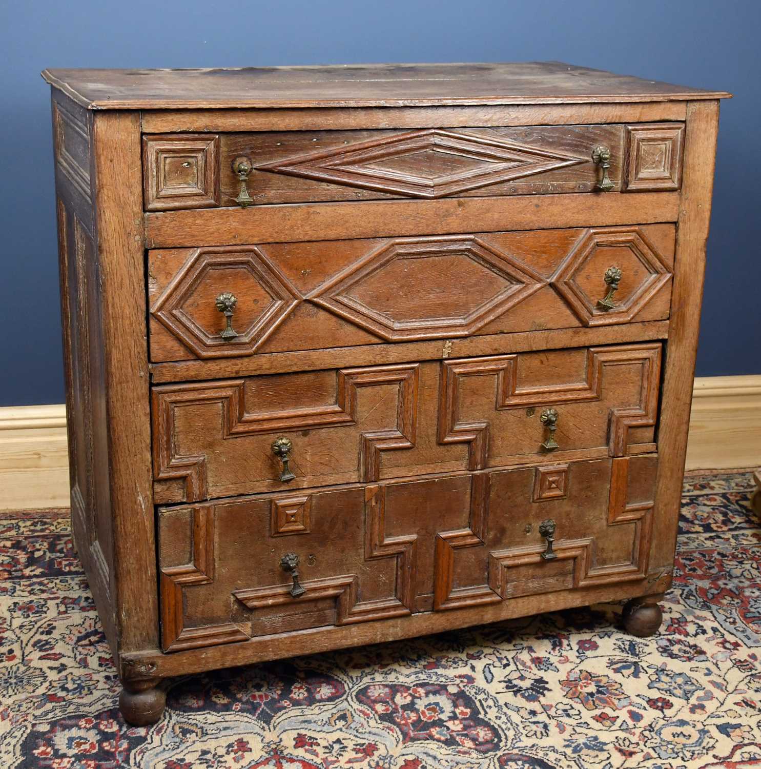 A 17th century and later oak chest, with four fielded panelled long drawers, on turned feet,