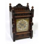A late 19th century German oak cased mantel clock with four turned finials above brass face set with