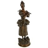 AFTER MAURICE MAIGNAN (French, 1842-1946), a bronze figure of a woman holding a pipe with a bird