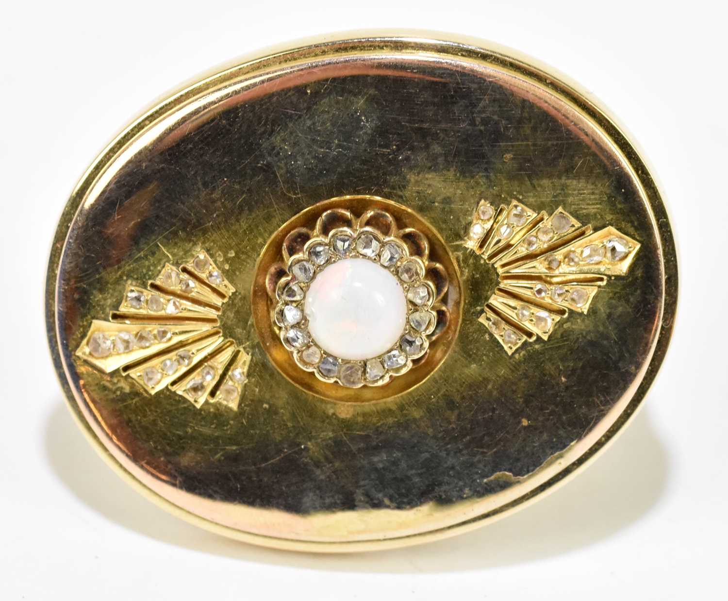 A yellow metal oval plaque brooch centred with an opal cabochon within a border of tiny rose cut