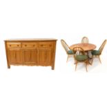 ERCOL; a light elm dining suite comprising drop-leaf table on swept supports, four spindle back