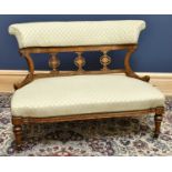 A Victorian inlaid walnut settee with open back, upholstered in a cream chequered material, on