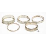 Four hallmarked and sterling silver snap bangles, together with a white metal filigree example,