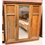 A late 19th century triple door wardrobe, with central bevelled mirrored door flanked by a pair of a