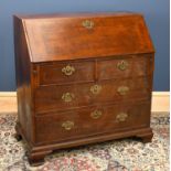 A George III oak bureau with fitted interior above two short and two long drawers, on bracket