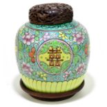 A Chinese porcelain ginger jar, brightly enamelled with flowers and symbols, with carved wood