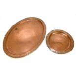 HUGH WALLIS; a large copper oval tray, width 56cm, with a similar circular dish with pewter