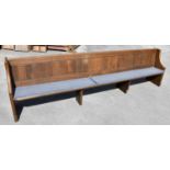 A large oak pew, with panelled back and solid seat, on standard end supports, height 84cm, length