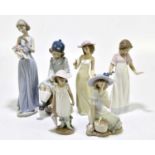NAO; a group of six ceramic figures to include a girl reading seated upon a barrel, shape number