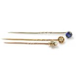 Two diamond set yellow metal tie pins, one modelled as a clover, the other as flower head, with a