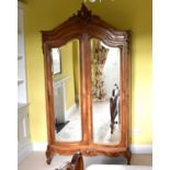 A reproduction French style armoire with mirrored doors and shaped top revealing two shelves, the
