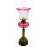 A Victorian oil lamp with clear and cranberry glass shade, etched with decoration of floral