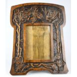 An Arts and Crafts carved beech easel back photograph frame of shaped form, carved with floral