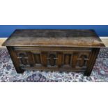 An reproduction oak coffer with three carved panels and hinged lid to top, height 52cm, width