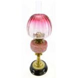 A late Victorian brass oil lamp with dome shaped cranberry and clear glass shade with etched