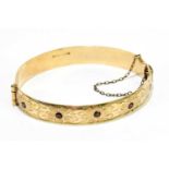 A 9ct rolled gold and garnet set snap bangle.