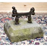 An early 19th century cast iron boot scraper, set into a canted stone base, overall height 25cm,