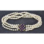 A cultured pearl four row choker set with a pearl and amethyst adorned yellow metal clasp, length