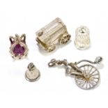 A group of five white metal charms, to include a man riding a pennyfarthing, a bell, a crown, a