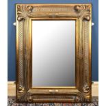 A modern decorative wall mirror, with moulded detail and central bevelled plate, approx 131 x