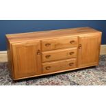 ERCOL; a light elm sideboard, the three central drawers flanked by two panelled cupboard doors,