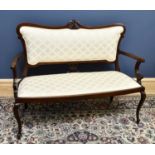 A late Victorian carved mahogany salon settee, with foliate ivory coloured upholstery, on cabriole