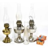 Two chrome oil lamps, height 30cm, with a brass oil lamp, five glass chimneys, etc.