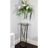 A modern patinated metal circular plant stand with round glass top, with a large champagne style